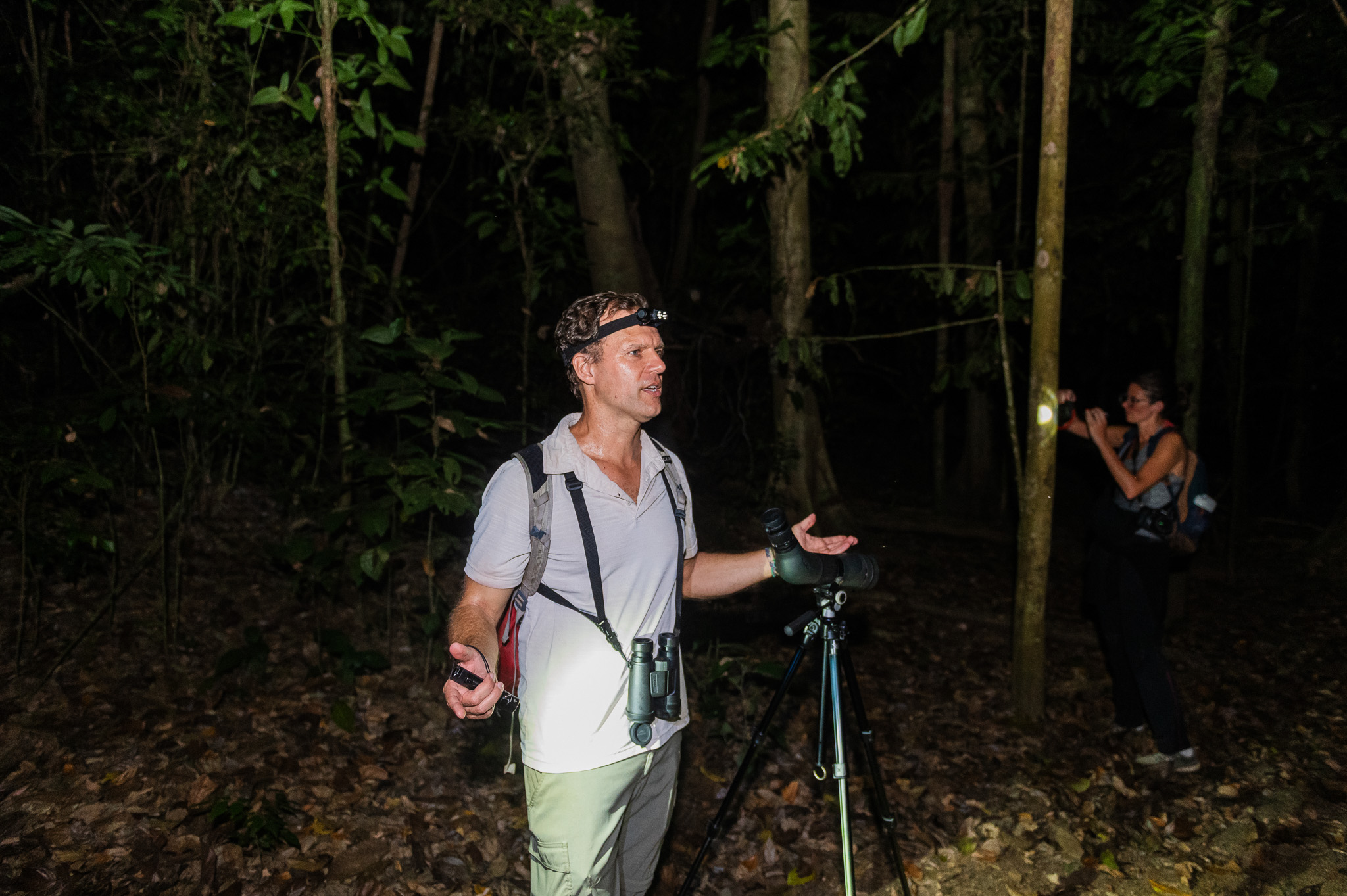 Naturalist guide Ryan Meczkowski leading a night walk in the Costa Rican rainforest with binoculars, headlamp, and spotting scope